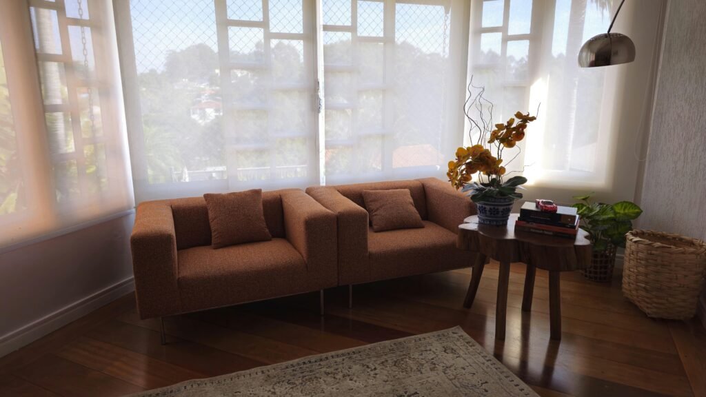 A stylish, minimalist living room interior featuring a cozy sofa, side table with plants, and natural light.