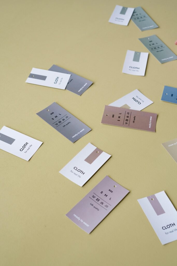 Scattered clothing tags on a neutral background, showcasing colors and designs.