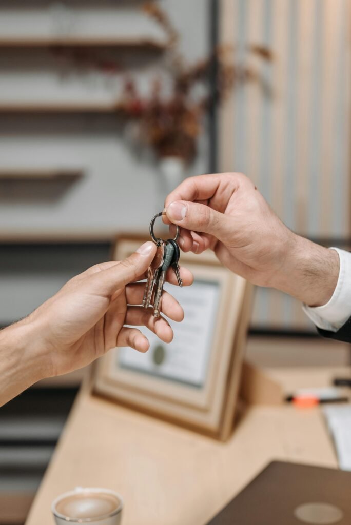 A real estate agent handing over house keys, symbolizing property ownership transfer.